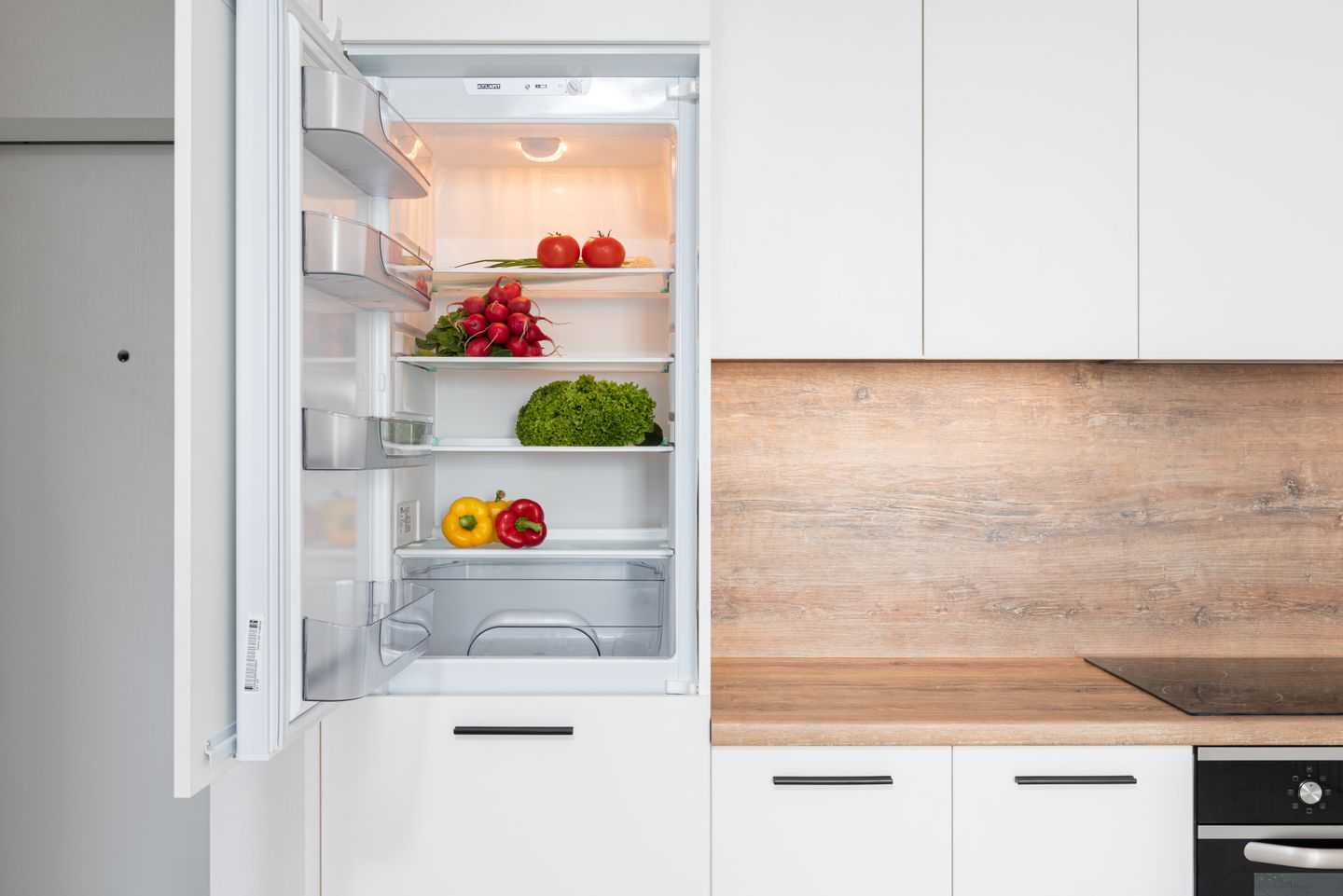 Fresh vegetables stored in an open refrigerator in a modern kitchen