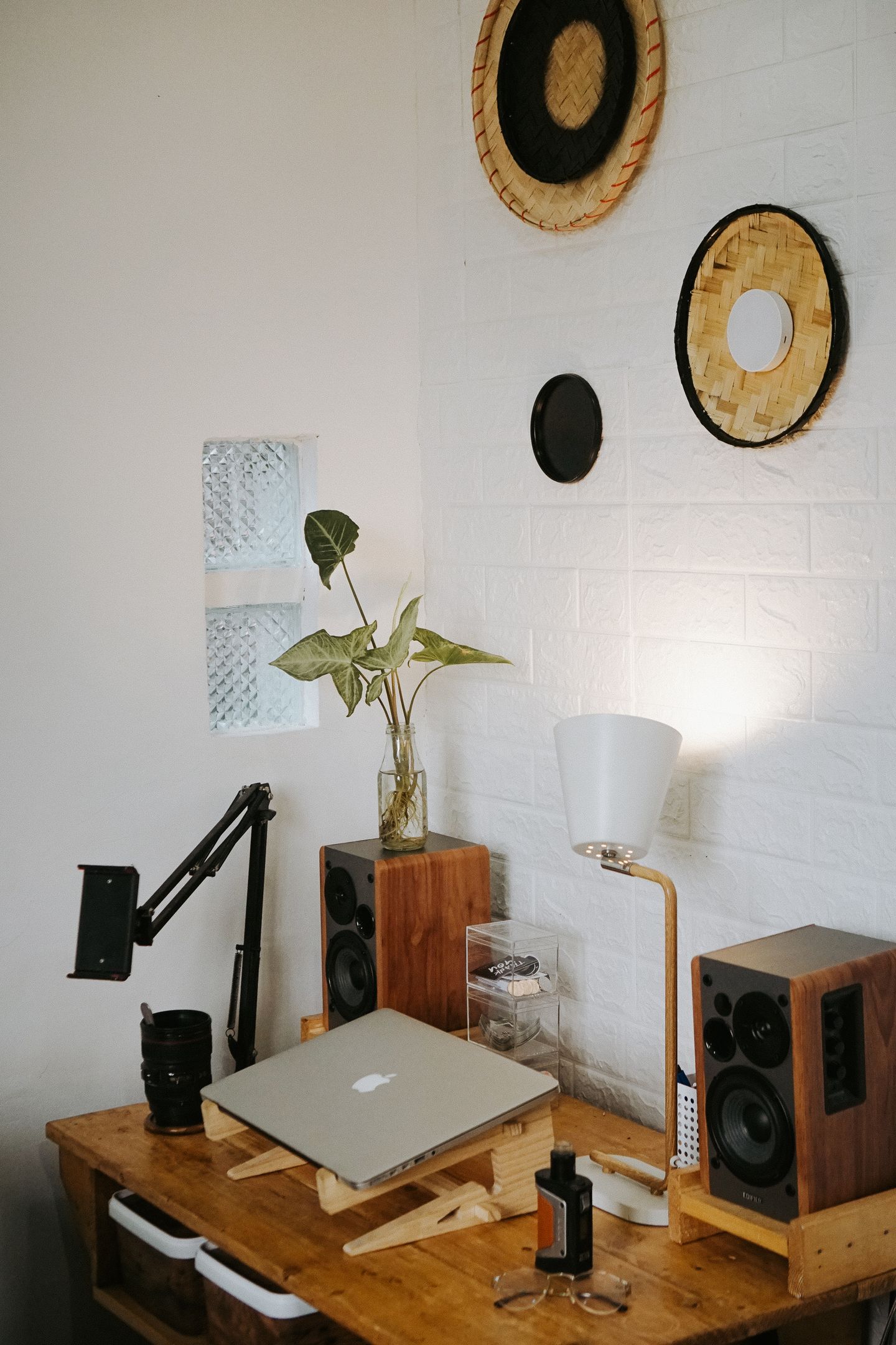 A compact home office with a laptop, speakers, and a warm desk lamp