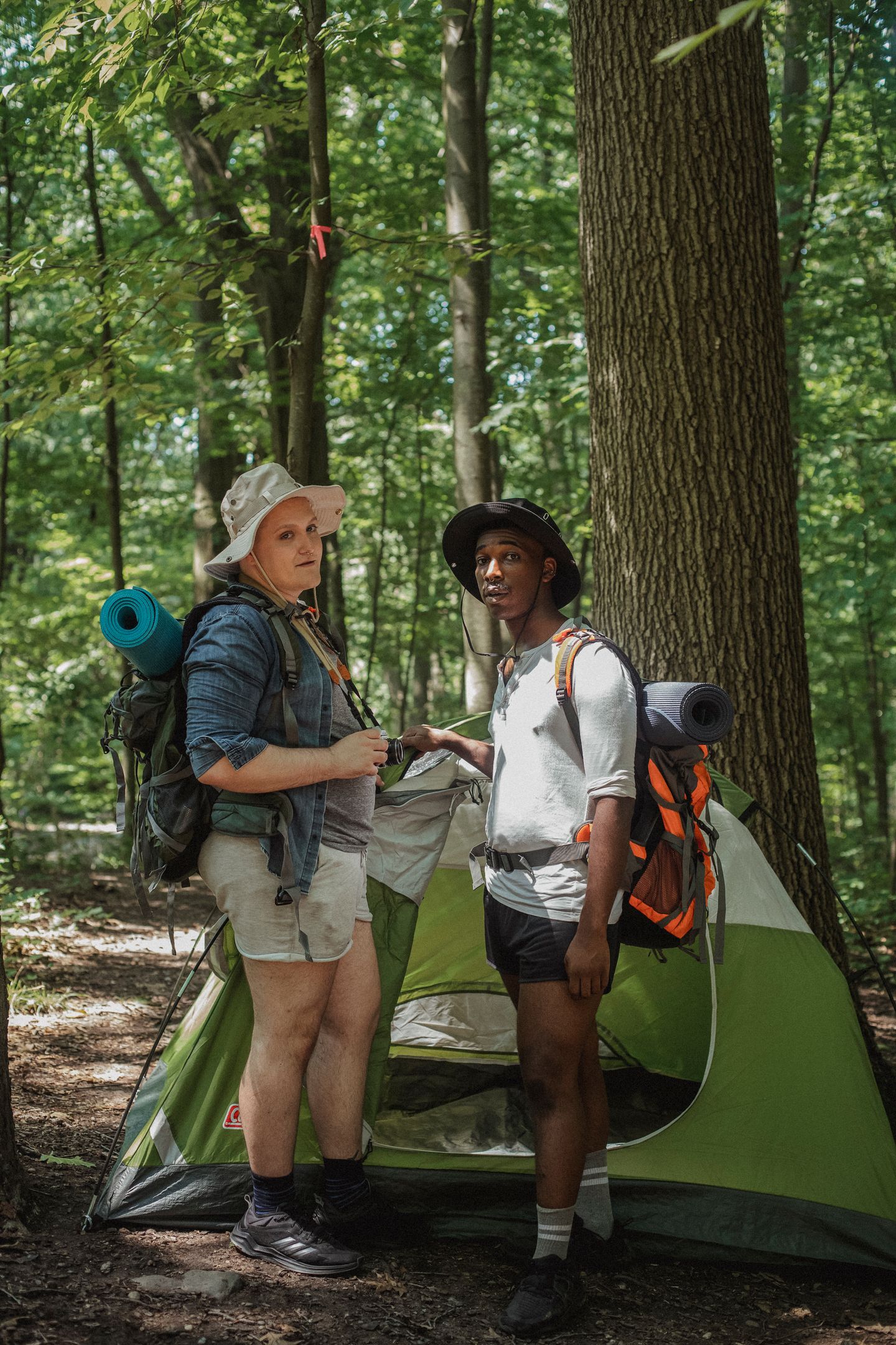Campers taking a break beside a tent in a green forest