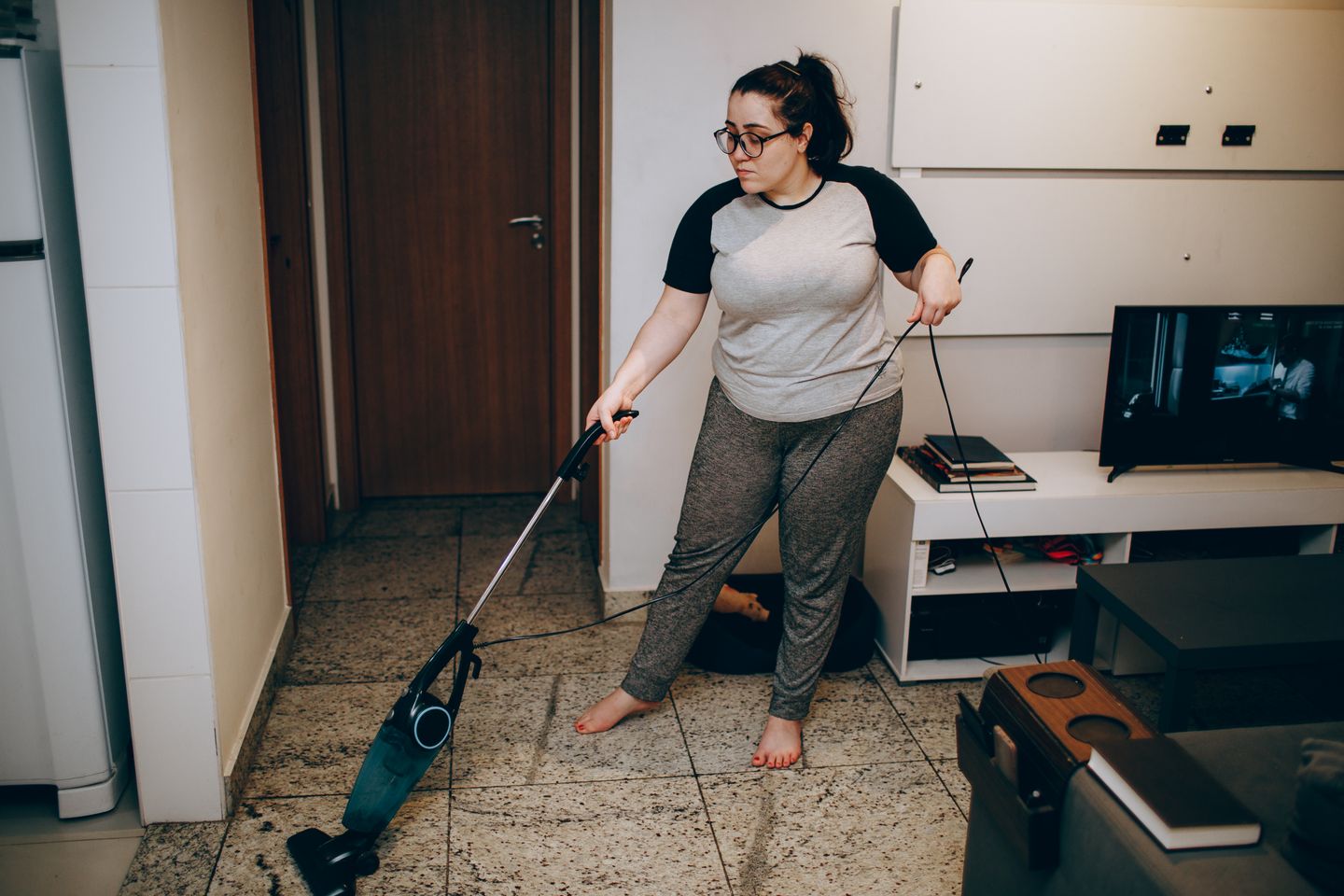 A woman vacuuming a living room as part of a regular home-cleaning routine