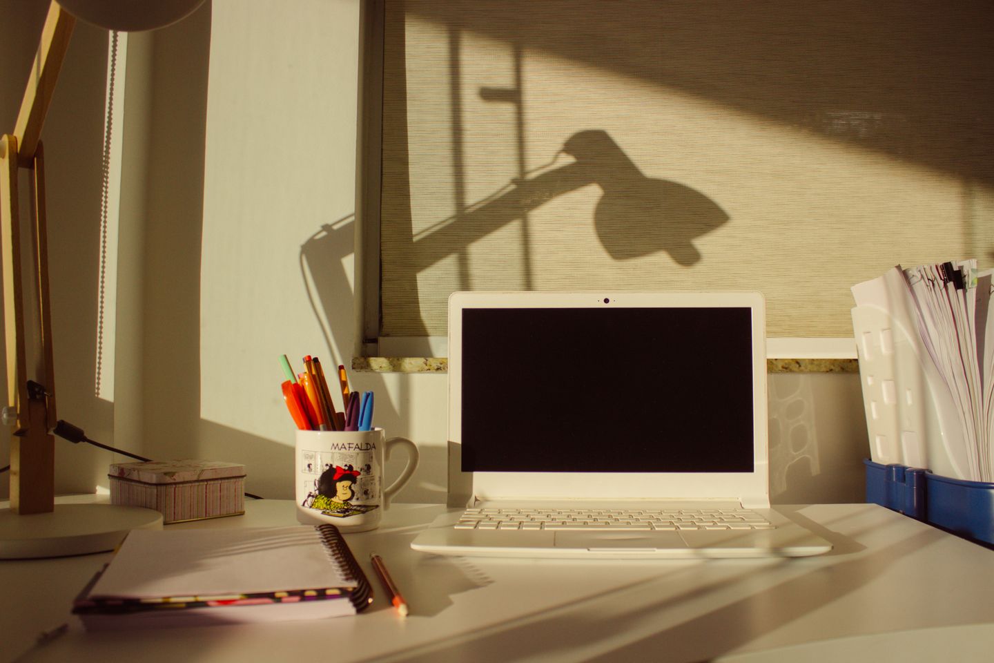 A laptop and notebook arranged on a tidy home-office desk