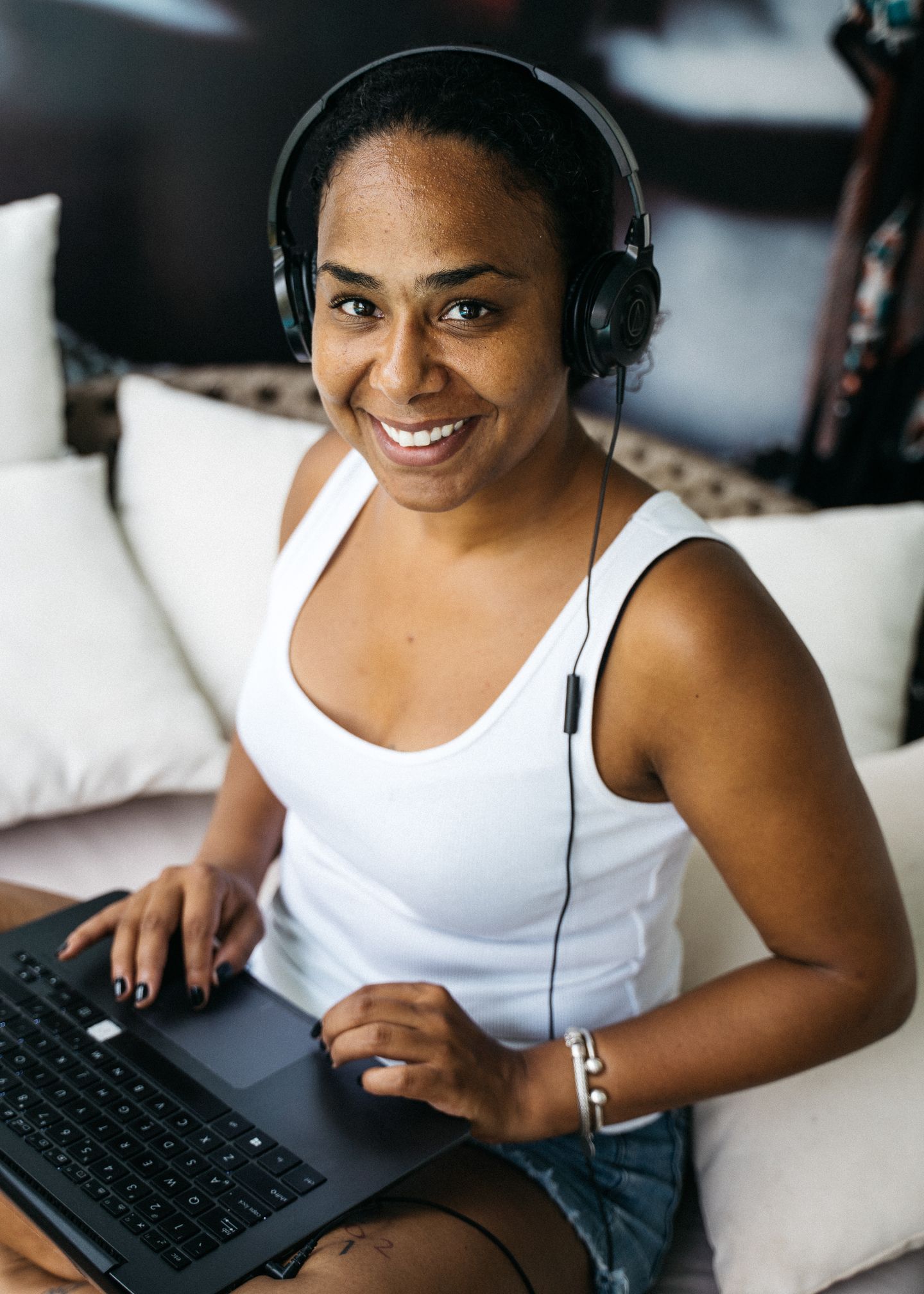 A woman using headphones while working from a laptop at home