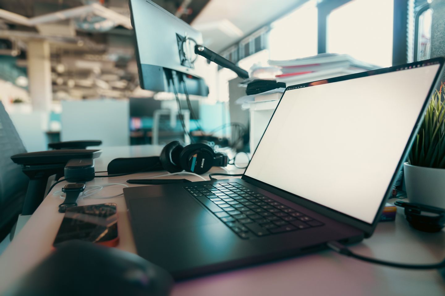 A laptop, monitor, and headphones arranged on a contemporary work desk