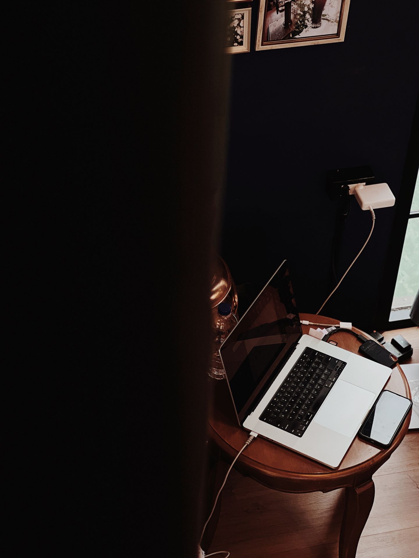 A minimalist work corner with a laptop, phone, and charging accessories