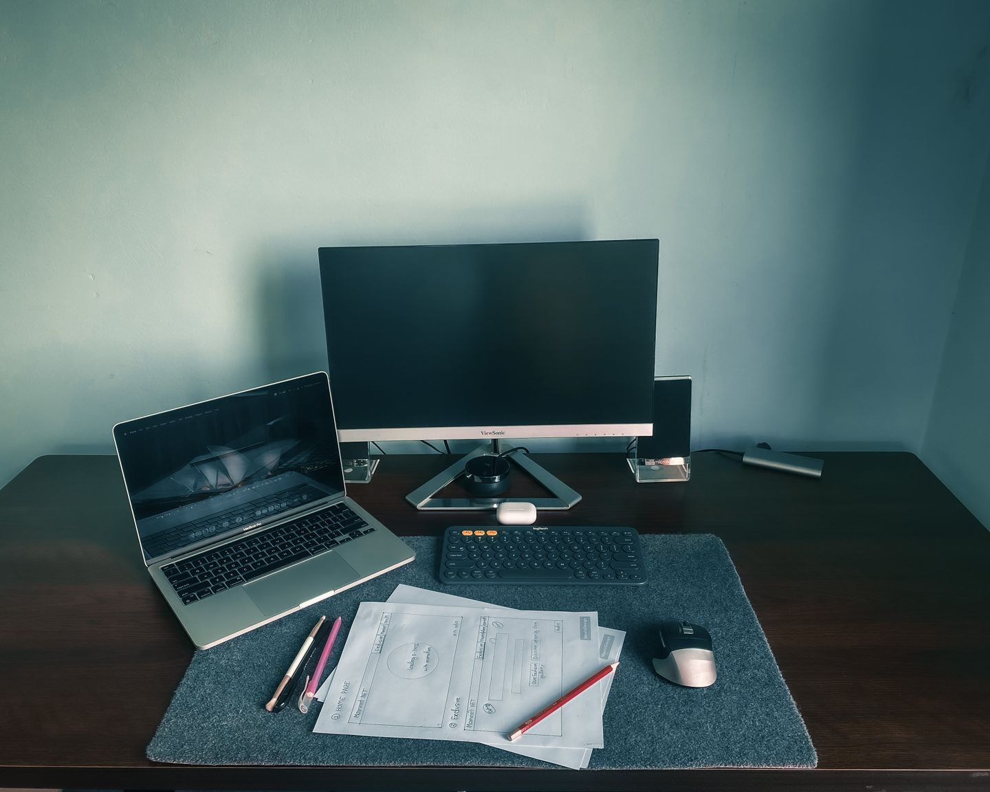 A home workstation with a laptop, desktop monitor, keyboard, and papers