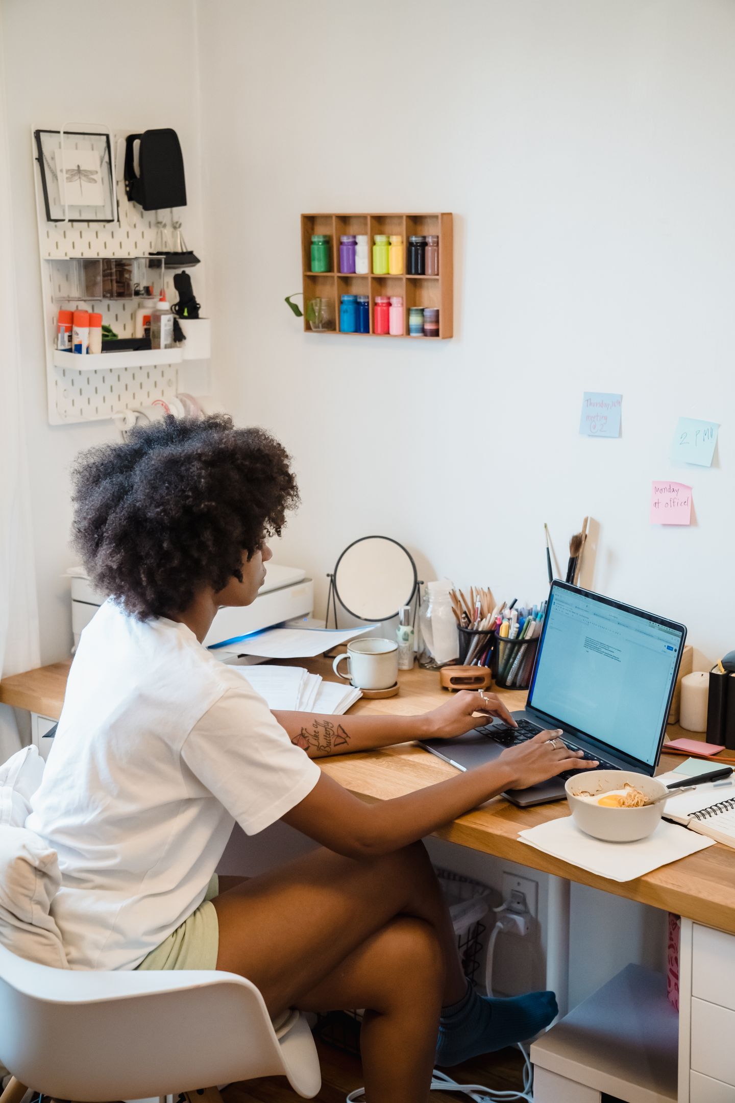 A home worker using a laptop beside notebooks and everyday desk items