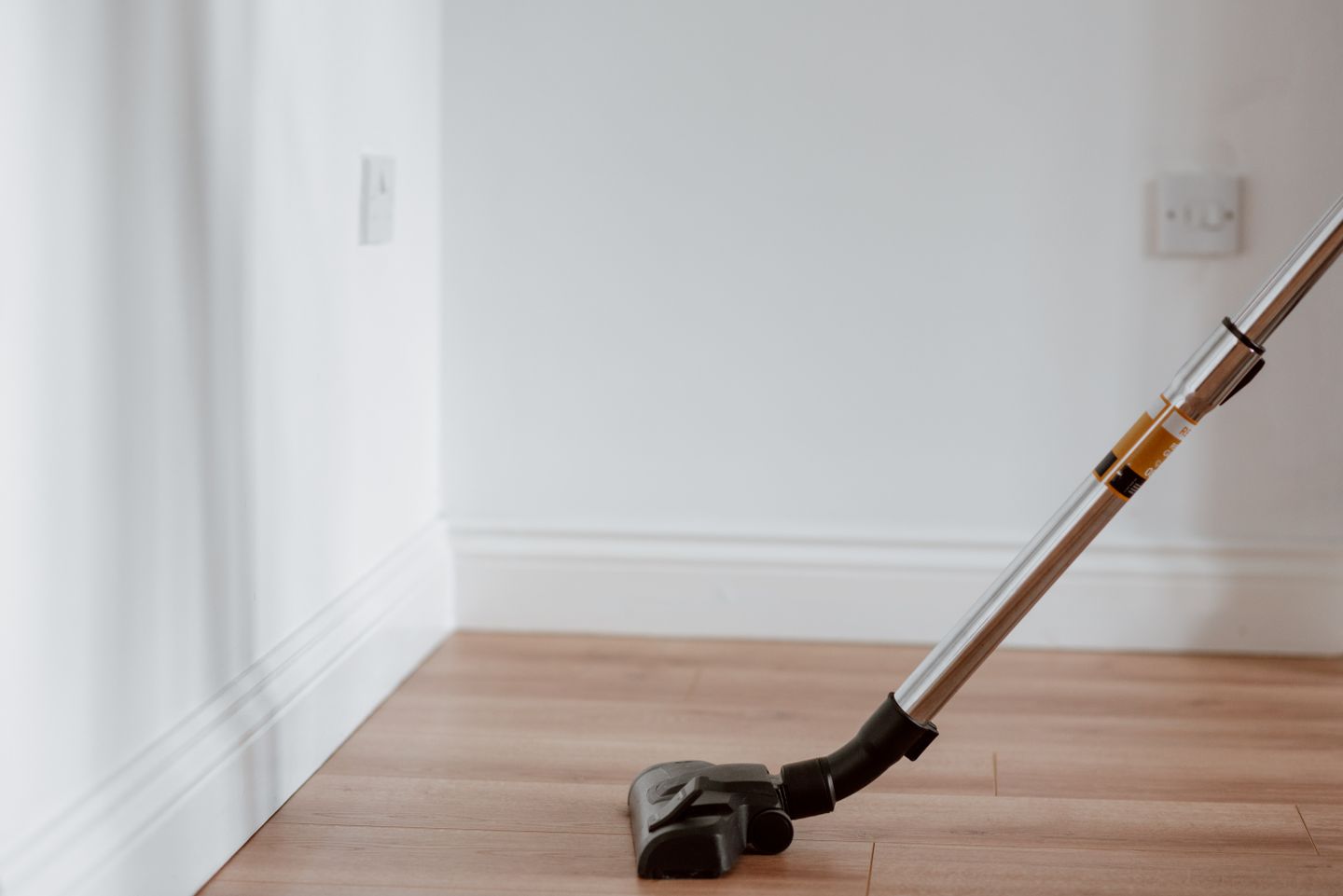 A vacuum cleaner moving across a sunlit apartment floor