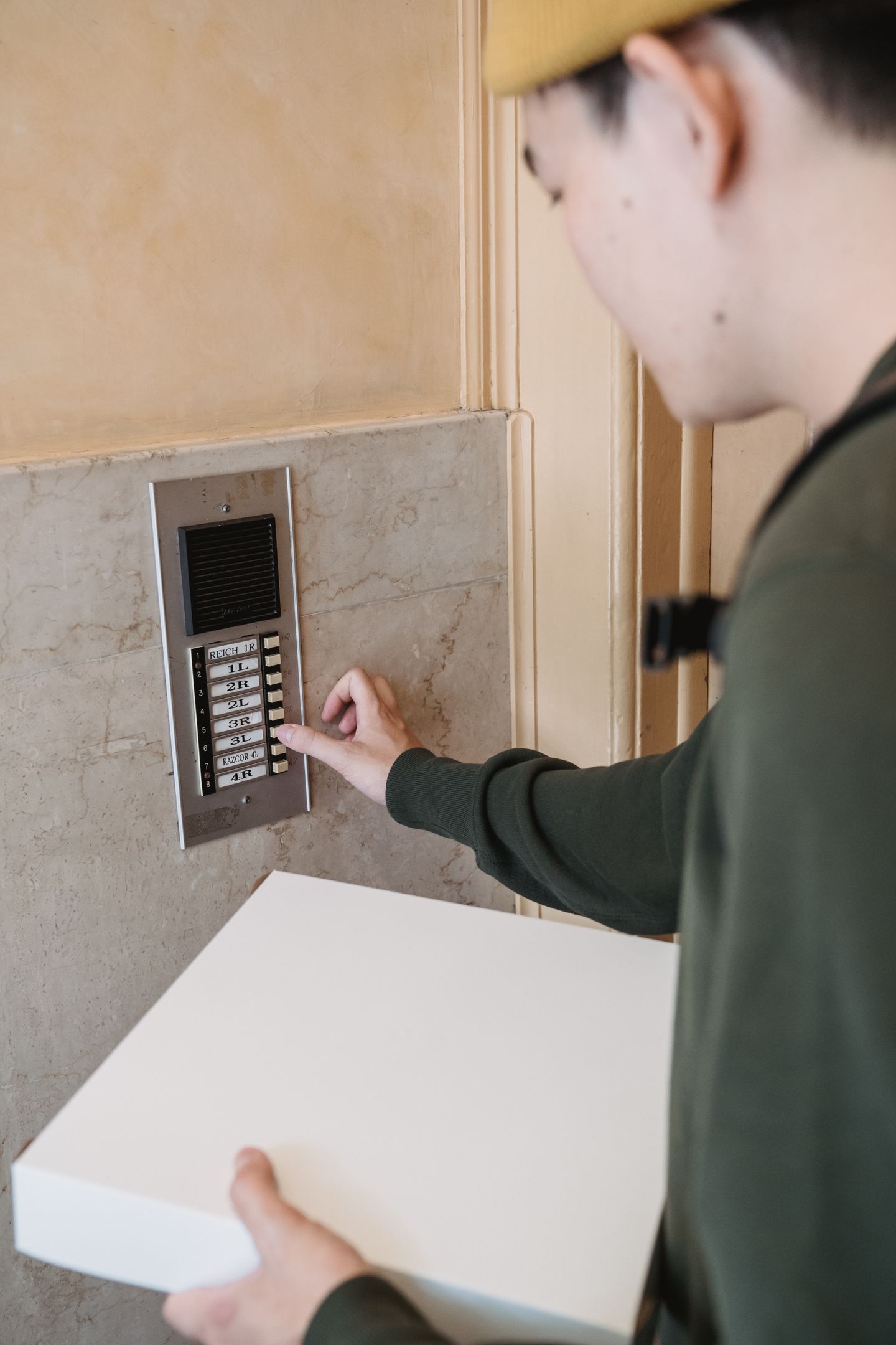 A delivery person using an intercom at an apartment entrance